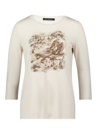 Langärmeliges cremefarbenes Hemd mit einem Grafikdruck mit den Worten "GLITTER", "glam" und "SPARKLE" sowie braune High-Heels, verziert mit Strasssteinen.