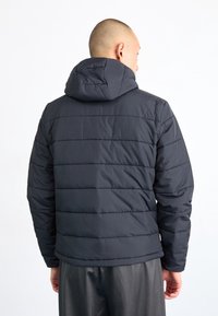 Ciemnoszara pikowana kurtka puchowa z kapturem, posiadająca pikowaną teksturę i poziome szwy. Prosty design, bez widocznych logo ani ozdób.
