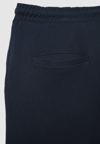 Marineblaue Sweatpants mit strukturierter Oberfläche, ausgestattet mit elastischem Bund und einer einzelnen Gesäßtasche mit geschwungener Öffnung.
