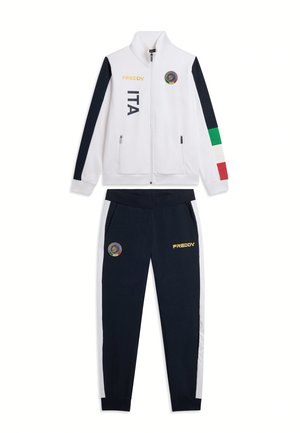 Tuta bianca e blu navy con strisce tricolore sulle maniche, scritta ITA e loghi del marchio Freddy su giacca e pantaloni.