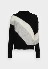 Pull noir, blanc et gris avec un design géométrique. Matière douce, col roulé, manches longues avec une fente latérale et des détails minimalistes.