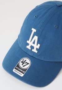 Blue baseball cap made of cotton twill, featuring white embroidered "LA" logo and a black circular tag with "47 Clean Up Adjustable."