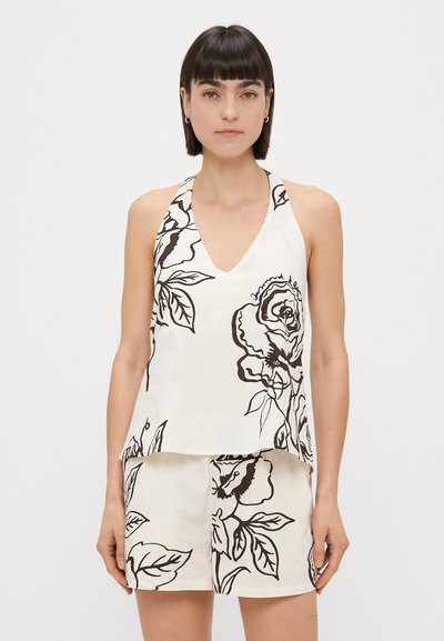 Top bianco con scollo a V e bretelline, decorato con grandi stampe floreali nere. Il tessuto sembra liscio e leggero, con una vestibilità ampia.