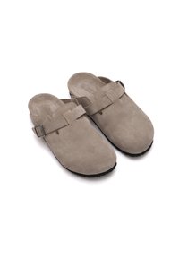Zoccoli in suede grigio con suola piatta, apertura ampia e una cinghia fissata con una fibbia argentata. Tessuto morbido e design minimal.