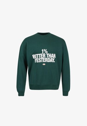 Donkergroene sweatshirt met ronde hals en witte tekst "1% BETERE DAN GISTEREN" gecentreerd op de voorkant.