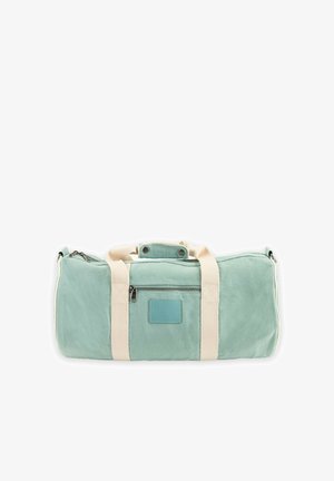 Bolsa de lona rectangular color verde claro con correas beige, bolsillo frontal con cremallera y asa superior asegurada con botones de presión.
