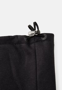 Juodas tekstilinis viršus su nosėjimo virvele, su sidabriniu užsegimu. Medžiaga atrodo minkšta su šiek tiek tekstūros.