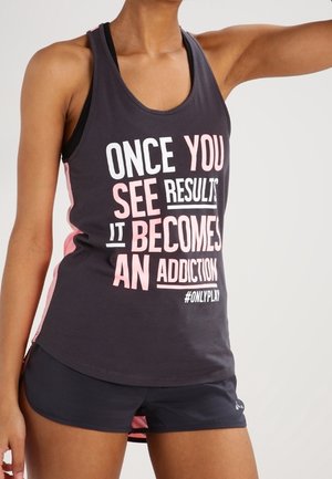 Kobieta nosząca czarny i różowy sportowy top z napisem "Once you see results it becomes an addiction" i czarne szorty.