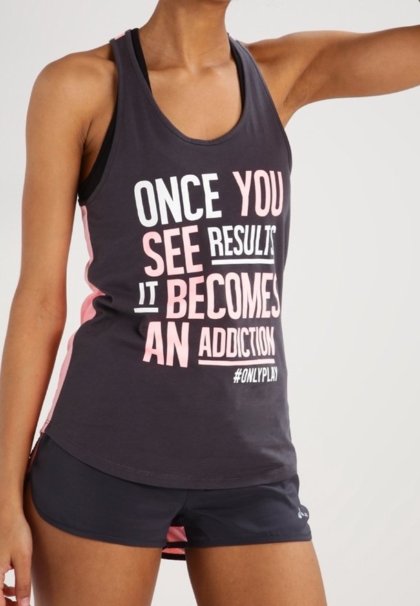 Femme portant un débardeur de sport noir et rose avec le texte "Once you see results it becomes an addiction" et un short noir.