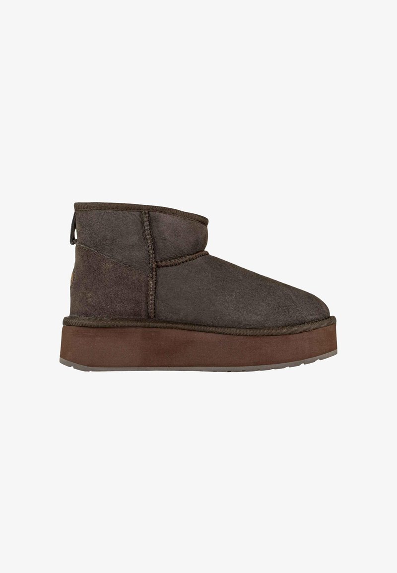 Stivale alla caviglia in suede marrone con tomaia imbottita, dettaglio del logo circolare e una spessa suola in gomma marrone. Presenta cuciture e un tassello per l'aggancio.