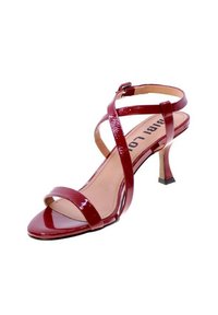 Sandalo con tacco in vernice rossa, con fasce incrociate, punta aperta e tacco a stiletto squadrato. Finitura liscia e design minimalista.