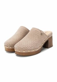 Mule in suede beige con design perforato, con una punta arrotondata. Decorato con borchie dorate lungo la base e un tacco in legno marrone.