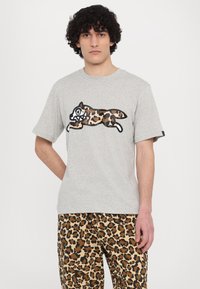Gray cotton t-shirt featuring a large, cartoonish leopard print design with exaggerated features. Loose fit and short sleeves.