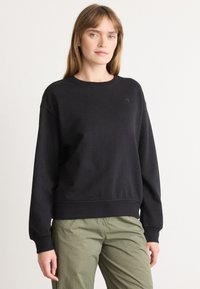 Čierny crewneck sveter s rebrovanými manžetami a lemovaním, s nenápadným logom na hrudi. Vyrobený z mäkkej zmesi bavlny.