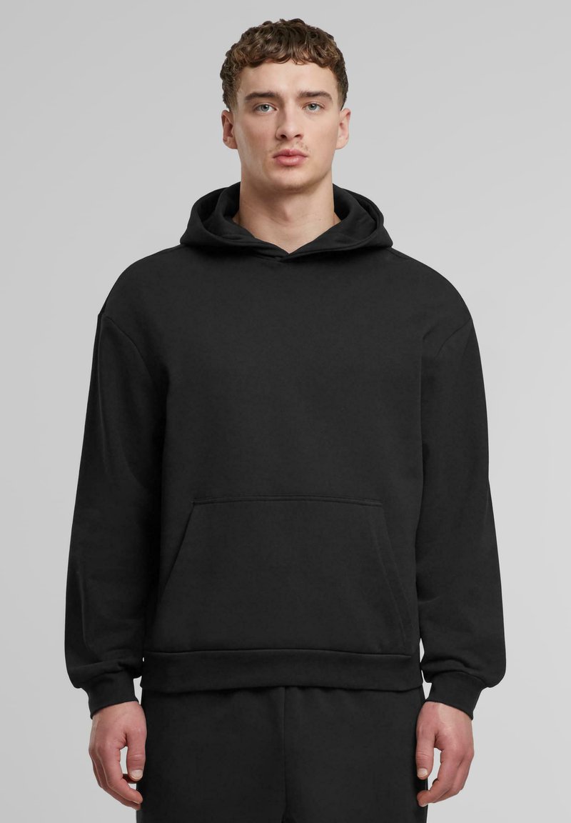 Schwarzer Hoodie aus weichem Stoff, mit einer geräumigen Vorderseite, breiten Bündchen und einer Kordelzugkapuze. Einfaches, minimalistisches Design.