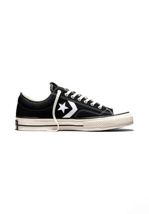Sort lavtstående lærredsneaker med hvid stjerne-logo, hvide snørebånd og tyk hvid gummisål med sorte striber.