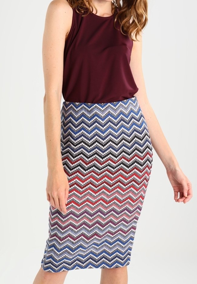Top sin mangas burdeos combinado con una falda ajustada de patrón de zigzag multicolor en tonos azules, rojos y negros; tela texturizada.