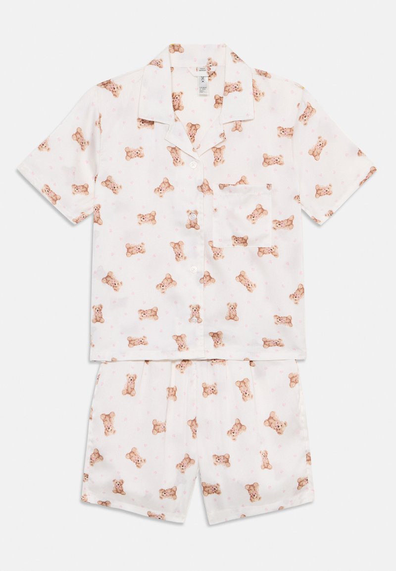 Kortärmad pyjamaset i mjukt tyg, med en vit bakgrund prydd med spridda nallebjörnar och hjärtan, inkluderar en skjorta med knappar och shorts.