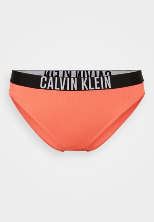 Oranžinė gumbinė bikinio apačia su juodu elastingu juosmeniu, ant kurio yra „CALVIN KLEIN“ tekstas. Lygi tekstūra ir prigludusi forma.