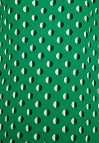 Helles grünes Gewebe mit einem sich wiederholenden Muster aus halbkreisförmigen Formen in Weiß und Dunkelgrün. Glatte Textur, leichtes Aussehen.