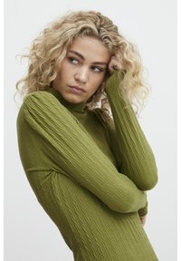 Maglietta verde a maniche lunghe con collo alto. Presenta un motivo a coste e un design aderente, che evidenzia la morbidezza del tessuto.