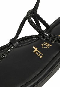 Svarta lädersandelar med en texturerad ovandel dekorerad med svarta rhinestones, platt sula och präglad logotyp, utformade för komfort.