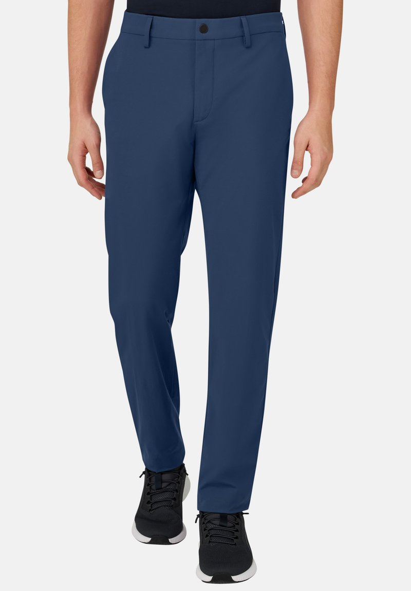 Marineblaue Hose aus glattem Stoff, mit Knopfverschluss, seitlichen Taschen und geradem Bein. Kombiniert mit schwarzen Sneakers.