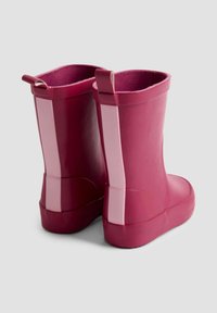 Bottes en caoutchouc d'une teinte rose profond avec une texture lisse. Présentent une bande contrastante rose clair sur le côté et une boucle de traction à l'arrière.