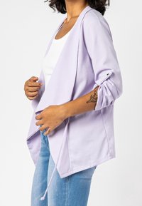 Bunda v barvě levandule z lehké látky, s ohrnutými rukávy, stahováním v pase a otevřeným předním dílem.