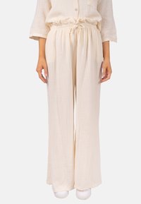 Leichte, cremefarbene weit geschnittene Hosen aus strukturiertem Stoff mit elastischem Bund und Kordelzug, die eine lockere Passform bieten.