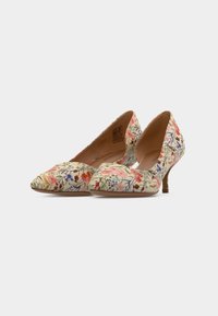 Paire de chaussures à talons hauts beige avec imprimé floral rose, rouge et bleu, bouts pointus et talons fins sur fond blanc.
