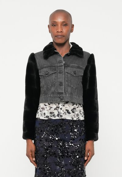 Veste coupe courte avec corps en denim gris, manches en fausse fourrure noire, fermeture à boutons et col classique. Portée sur un haut à motif floral et une jupe pailletée.