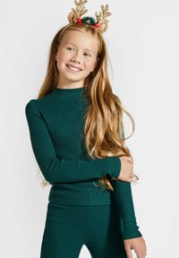 Zielony, prążkowany top z długim rękawem wykonany z teksturowanego materiału, w komplecie z dopasowanymi spodniami. Złota opaska na głowę z porożem renifera z czerwonymi akcentami.