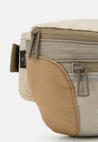 Beige en tan nylon tas met een gekapte textuur, dubbele ritssluiting en een Paul Smith label. Heeft een ruitpatroon aan één kant.