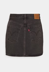 Mini-jupe en jean noir avec poches arrière, passants pour ceinture et un patch en cuir marron avec le logo Levi's sur la ceinture.
