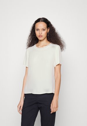 Kurzärmlige, helle Bluse mit glatter, leichter Textur. Ausgestattet mit einem runden Ausschnitt und einer lockeren Passform, kombiniert mit dunklen Hosen.