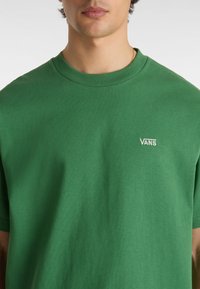 T-shirt verde in cotone con colletto a girocollo, maniche corte e logo "VANS" ricamato sulla parte sinistra del petto.