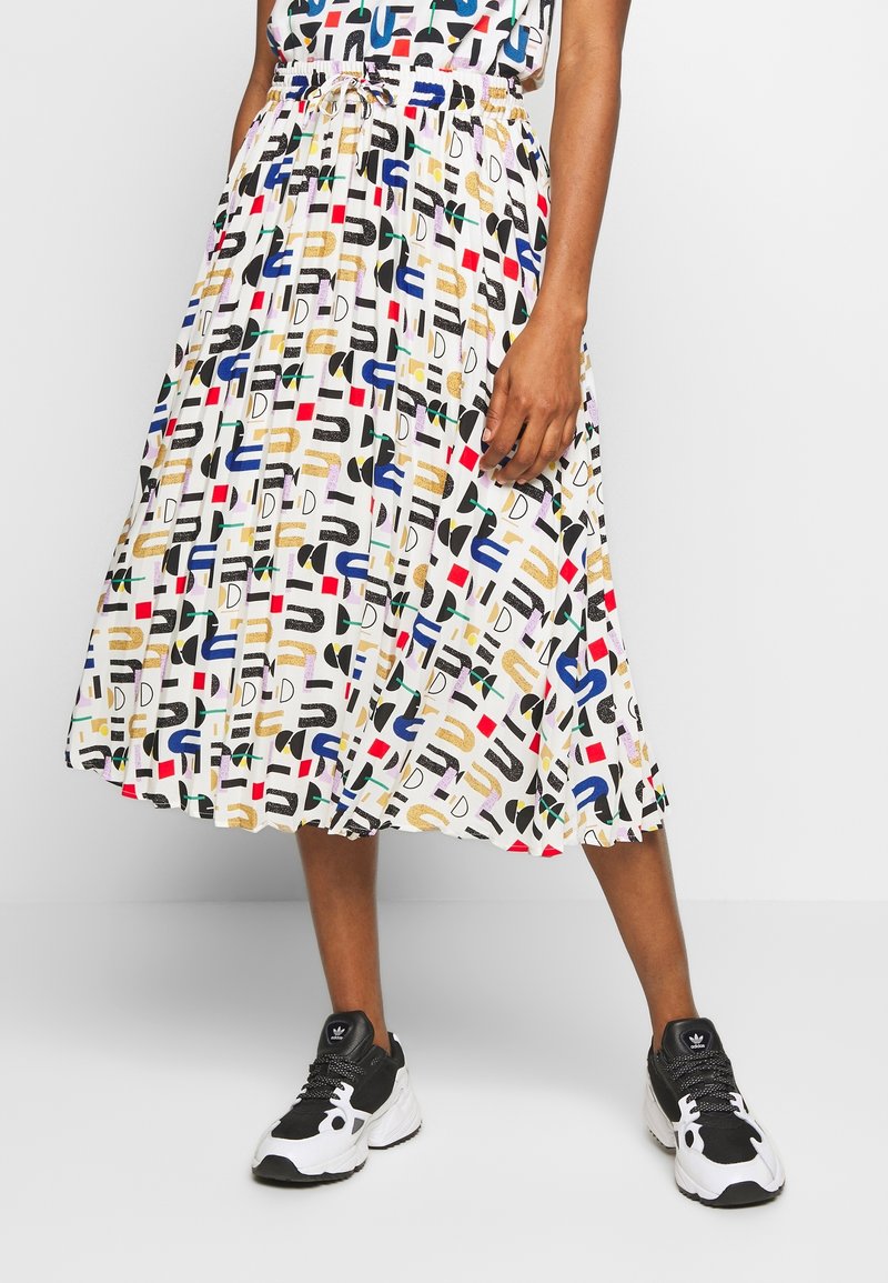 Jupe midi plissée en tissu léger présentant un imprimé géométrique multicolore sur fond blanc. Taille élastique avec détail de cordon de serrage.