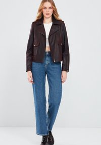 Bordeaux leren cropped jack met brede revers, ritssluiting en voorkruiszakken, gecombineerd met hoogzittende blauwe rechte jeans en zwarte laarzen.