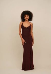 Vestido de noite borgonha com silhueta ajustada, alças finas, decote em V profundo e fenda alta na perna para um detalhe adicional. Textura suave.