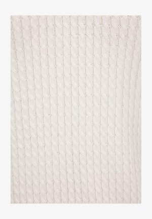 Primo piano di tessuto bianco lavorato a maglia con motivo a trecce verticale e piccoli dettagli traforati.