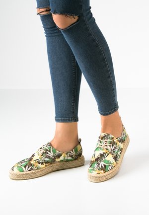Espadrilles dengan pola bunga dengan desain hijau, kuning, dan coklat. Terbuat dari kain dengan sol tali jute. Ujung bulat dan gaya ikatan.
