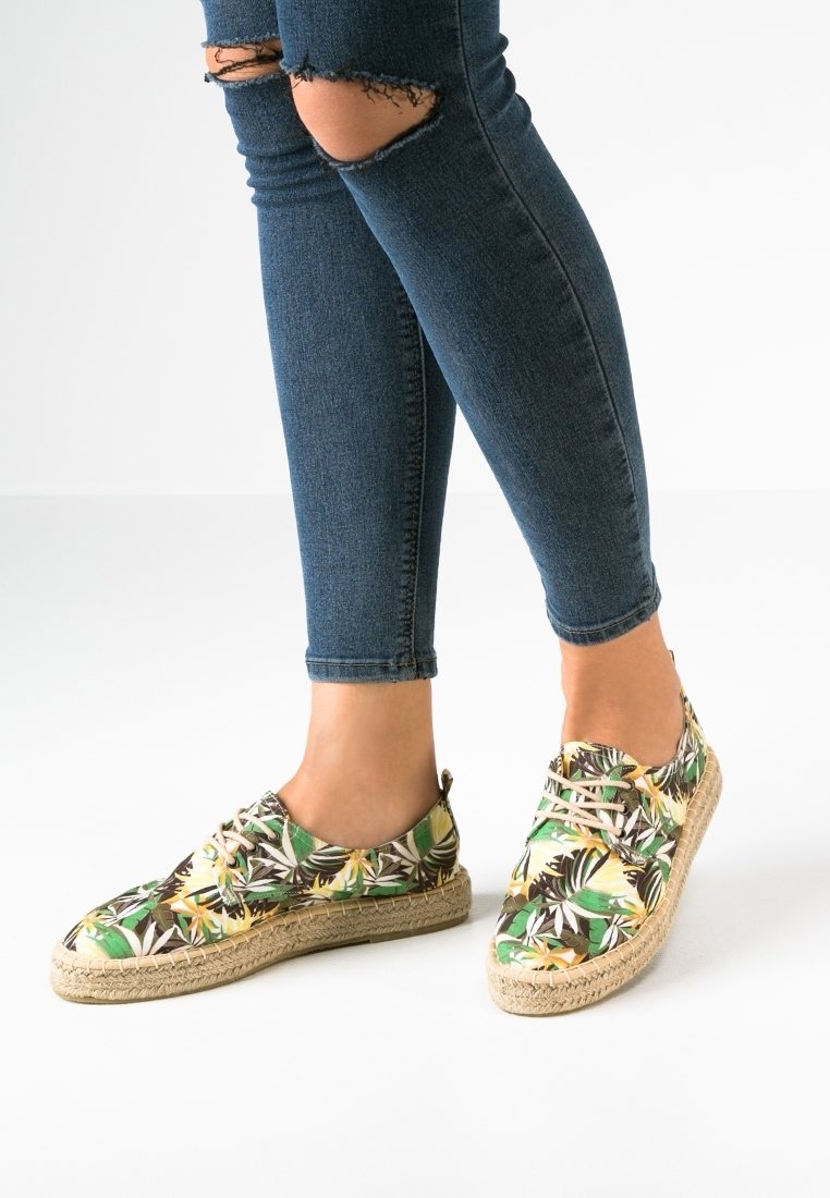 Espadrilky s květinovým vzorem v zelené, žluté a hnědé barvě. Vyrobeny z látky s jute podešví. Kulatá špička a šněrovací styl.
