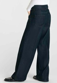 Brede, donkere denimbroeken met een hoge taille, voorzien van twee achterzakken en een gladde, gestructureerde afwerking.