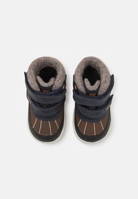 Brune og marineblå støvler til småbarn med borrelåsremmer, filtforing og gummisåler med hvite sømmer og avrundet tådesign.
