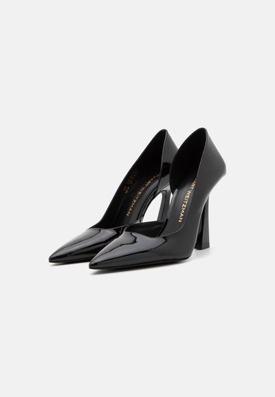 Chaussures à talons hauts en cuir verni noir avec un bout pointu et un design découpé arrondi, dotées d'un talon épais et d'un logo doré à l'intérieur.