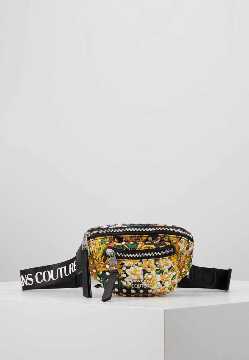Petite sacoche ceinture Versace Jeans Couture à motif floral, ornée de clous argentés, avec une sangle noire ajustable et deux compartiments zippés.