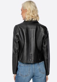 Schwarze Lederjacke mit tailliertem Design, Reverskragen und Druckknöpfen. Strukturiertes Finish mit zwei Seitentaschen und cropped Länge.