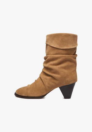 Hnedá semišová členková čižma s voľným sklonom, zaoblenou špičkou a nízkym, šikmým podpätkom. Hladká textúra s jemnými švami a oblými tvarmi.