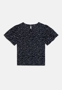 Blouse marine à manches courtes avec un motif de petits points blancs, col rond et détail en keyhole au dos ; tissu léger avec une texture douce.